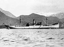 Side view of a ship upon water, with mountains visible in the background