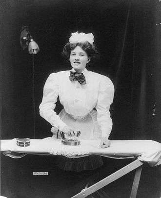 A domestic servant ironing a lace doily with GE electric iron, ca. 1908
