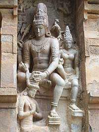 Granite sculpture of a devotee in kneeling posture garlanded by Shiva and Parvathi in sitting posture