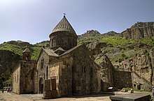 Stone church with a central tower topped by a conical roof.
