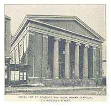 Black and white photograph of a building with columns, stairs leading to the street, and a neoclassical pediment