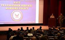 Training is being conducted to educate Naval War College personnel ofr United States Navy transgender policies on January 10, 2017. View is from the audience showing a majority of the screen, with the lecturers (Captain Tamara Graham and Command Master Chief Craig Cole) standing to the right of the screen at a lectern, facing the audience.