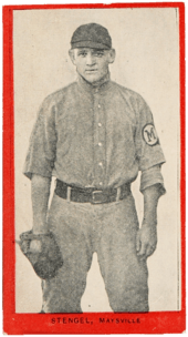 a young man in an old-style baseball uniform wears a glove and stares at the camera