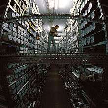 A man on a walkway between two high shelf racks loaded with ice core samples