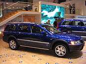 Passenger side view of blue XC70 OR with silver door trim, rocker trim and roof rails