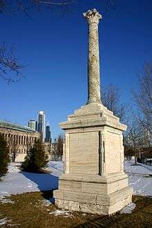 The ancient column on its base with the Chicago skyline in the background.