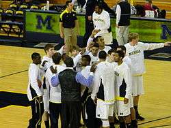 Men's basketball team in a pre-game huddle on the court