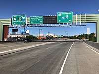 A split in a multi-lane freeway under construction with three green overhead signs. The left sign reads west Route 139 to U.S. Route 1 and 9 Interstate 280 Pulaski Skyway with two downward arrows, the middle sign reads Kennedy Boulevard Jersey City with two downward arrows, and the right sign reads New Jersey Turnpike Interstate 78 to Interstate 95 with two arrows pointing to the upper right.