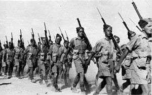 several men in desert uniform marching with rifles on their shoulders
