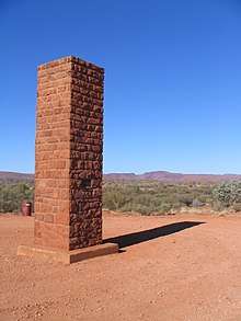 Red stone pillar monument in clearing