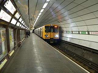 A Merseyrail train painted with a yellow front and grey sides. It is underground at Liverpool Central station.