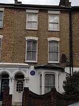 exterior of white house, with blue plaque on front wall
