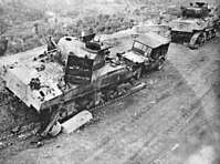 Two damaged tanks with their tracks visibly destroyed and a damaged Willy's Jeep displaying the 6th Armoured triangular flash