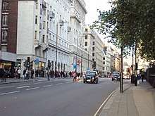 A street view of Piccadilly, showing buildings, two London taxis and a bus