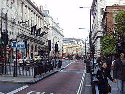 Street picture of Piccadilly with bus lane, road signs and the Meriden Hotel. Piccadilly circus is in the background