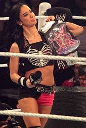 AJ Lee holding the WWE Divas Championship in a wrestling ring
