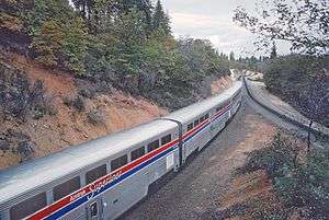 Silver railcars next to a hill