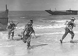 Soldiers disembarking a landing craft on a beach during training