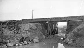 a black and white photograph of a railway bridge on an embankment