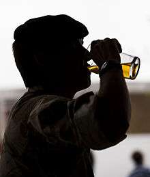 Silhouetted man drinking a glass of beer