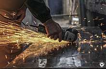 Bright sparks fly as a man grinds a piece of metal