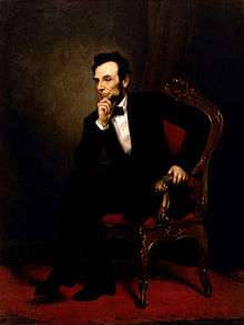 A painting depicting President Lincoln seated in an ornate wooden armchair.  He wears a black suit and bow tie.  He is leaning forward, legs crossed, with one hand on his chin.