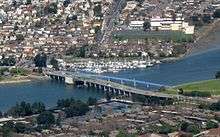 Aerial view of a bascule bridge (drawbridge) spanning the estuary separating Alameda Island from Bay Farm Island, which is now a peninsula connected to Oakland.