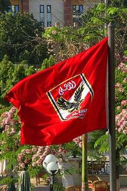 A flag with the crest of Egyptian association football club Al-Ahly, on a red background, can be seen.