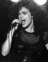 Black and white image of a woman with her eyes closed and mouth open, holding a microphone.