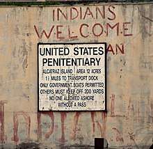 A sign that reads United States Penitentiary has graffiti above it saying "Indians Welcome".