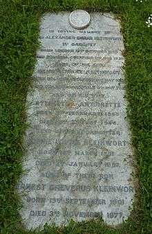 A granite horizontal headstone surrounded by grass