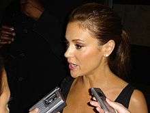 Alyssa Milano speaking into several audio recorders during an interview