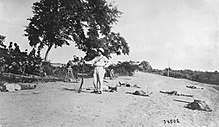 Black and white photo of a man standing among bodies lying on the ground