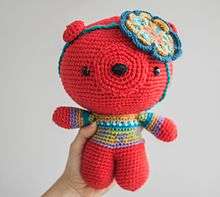 Amigurumi bear. Example of a large size amigurumi. Self made. Colors used are red, blue, and green. It has a flower decoration on the head.