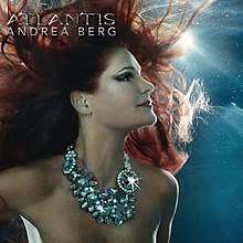 A red-haired woman underwater looking up. She is wearing a shiny pearl necklace. The words "Andrea Berg Atlantis" are written in silver in the top left corner.
