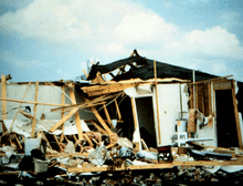 Significant tornado damage inflicted upon a home, with its exterior walls missing and some of its interior walls and roof destroyed