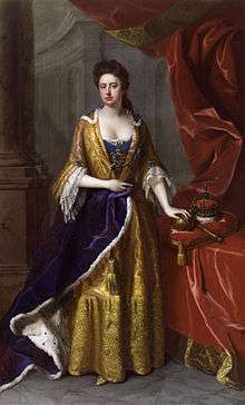 A full length portrait of a pale-skinned woman standing, left arm resting on an orb, itself on a cushion supported by a table.  Next to the orb is a crown and sceptre.  Thick red curtains frame the woman, who is dressed in yellow.  Her right arm holds a violet ermine robe.  Stone columns are visible behind her.