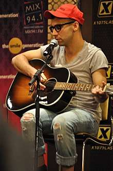 A picture of a man playing a guitar and singing into a microphone.