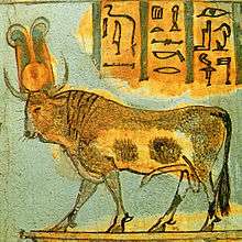 Painting of a bull on a platform. The bull has a yellow disk and a pair of feathers between its horns.