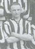 Head and upper torso of a white man with arms folded wearing a striped sports shirt; image apparently clipped from a team photo.