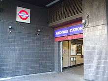 A doorway with a sign above it stating "ARCHWAY STATION" in white letters on a blue background all under two large, grey vents that are side-by-side