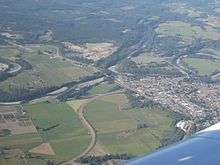 A small town surrounded by farmland and forestland, crisscrossed by rivers and roads.