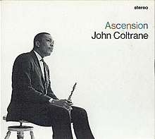 In a black-and-white photo, Coltrane sits on a stool facing right, wearing a three-piece suit and holding his saxophone between his legs. To the right, the word "stereo" appears in the upper corner in black, with "Ascension" written in multiple colors beneath it, followed by "John Coltrane" in black below that.