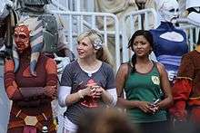 two female actresses with people in costumes around