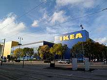 A blue building with "Ikea" written on the side in large yellow letters. Trees in the foreground.