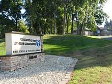 Photograph of the entrance sign, hill, and building.