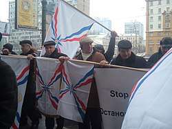 Warmly-dressed men holding Assyrian flags