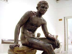 Bronze statue of seated male youth in a museum