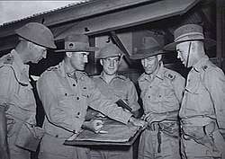 A group of military officers in conference around a map