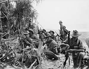 Australian infantrymen resting on a river bank before attacking Japanese positions near Matapau in January 1945